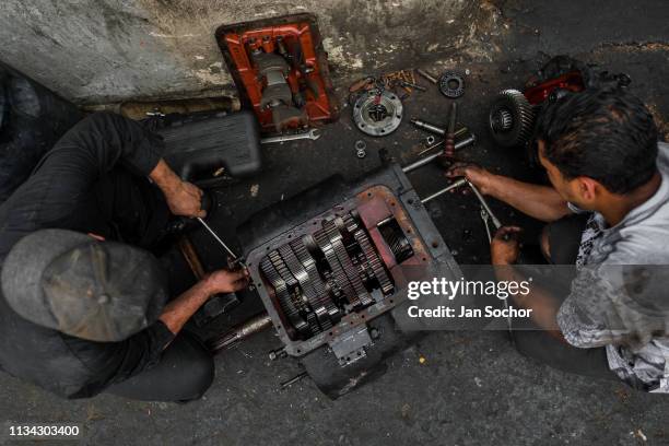 Colombian car mechanics work on a transmission in a car repair shop in Barrio Triste on November 29, 2017 in Medellin, Colombia. Barrio Triste is a...