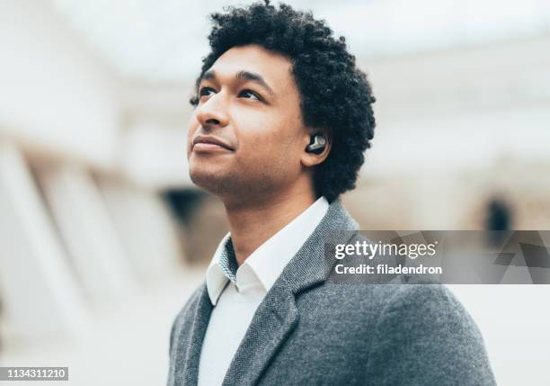 portrait de jeune homme avec des écouteurs sans fil - bluetooth photos et images de collection