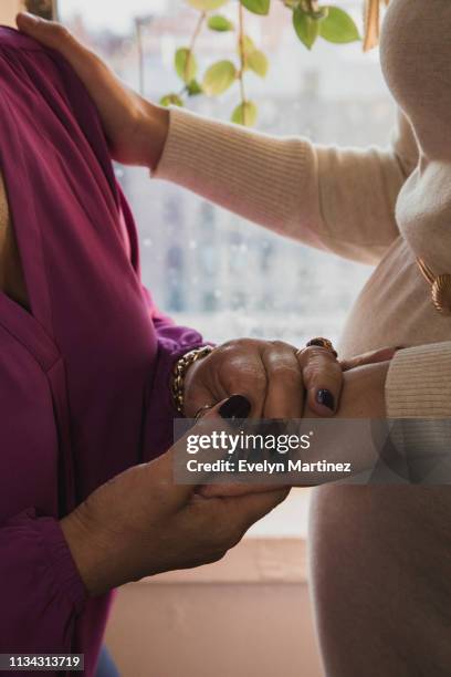 Mother holding daughter's hand. Daughter's hand on mother's shoulder.