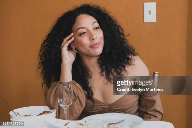 latina woman with her hand on her head listening to conversations at the dinner table. partial view of the table and plates. - dominican ethnicity bildbanksfoton och bilder