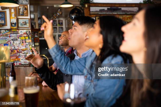 diverse group of friends watching game at sports bar - bar atmosphere stock pictures, royalty-free photos & images