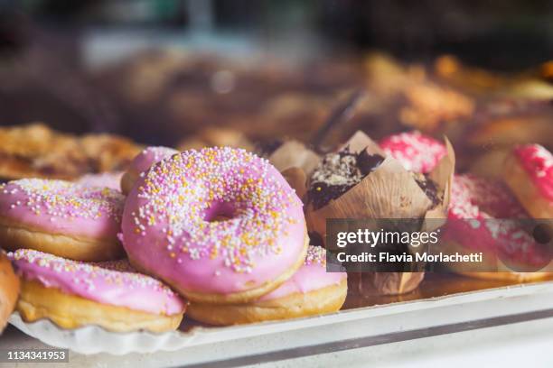 pink donuts in store window - ドーナツ ストックフォトと画像