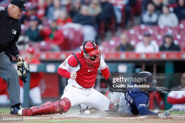 Ryan Braun of the Milwaukee Brewers scores ahead of the throw to Tucker Barnhart of the Cincinnati Reds after a two-run single by Jesus Aguilar in...