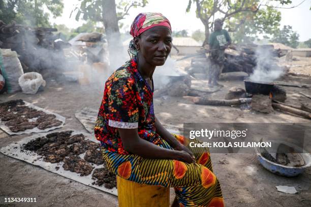 Ladi Kodi, a monthly beneficiary of Conditional Cash Transfer programme sit beside her black soap business in Garaku, Kokona Local Government,...