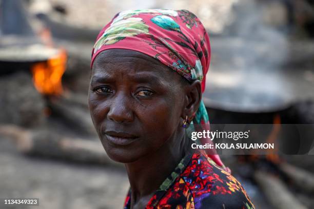 Ladi Kodi, a monthly beneficiary of Conditional Cash Transfer programme sit beside her black soap business in Garaku, Kokona Local Government,...