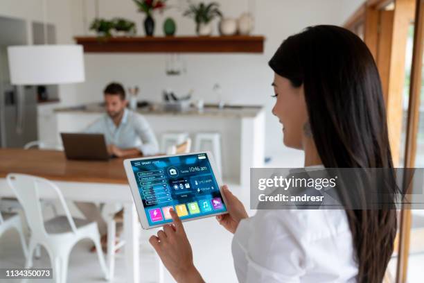 woman setting up the intelligent home system on her tablet computer - smart house stock pictures, royalty-free photos & images