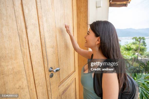 reiselaufende frau klopft an die tür einer unterkunft - knocking on door stock-fotos und bilder