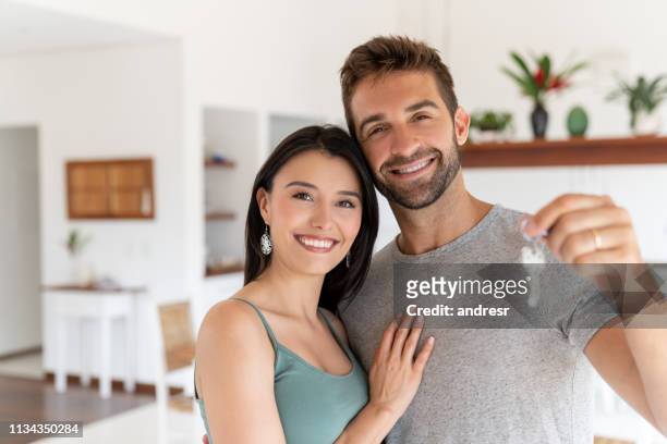loving couple holding keys to their new house - house keys stock pictures, royalty-free photos & images