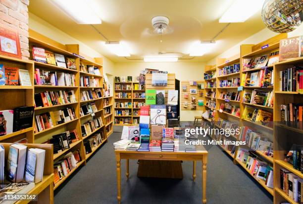 books on shelves and table in bookstore - librairie photos et images de collection