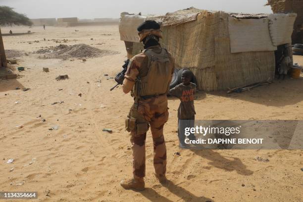 French soldier looks at a child as he patrols in the streets of Gossi, center Mali, on March 25, 2019. - A few kilometers from the Malian town of...