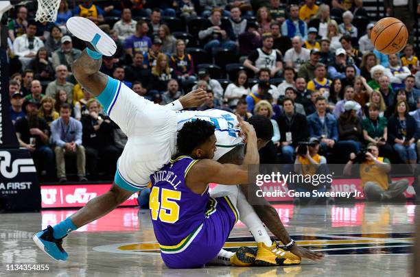 Dwayne Bacon of the Charlotte Hornets falls over Donovan Mitchell of the Utah Jazz in the first half of a NBA game at Vivint Smart Home Arena on...