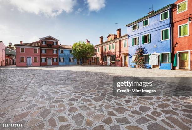 colorful homes surround a flagstone plaza - städtischer platz stock-fotos und bilder
