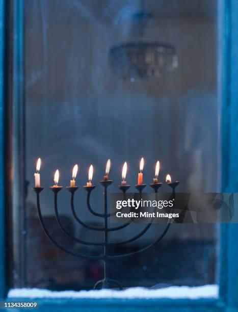 lit menorah on windowsill - menorah fotografías e imágenes de stock