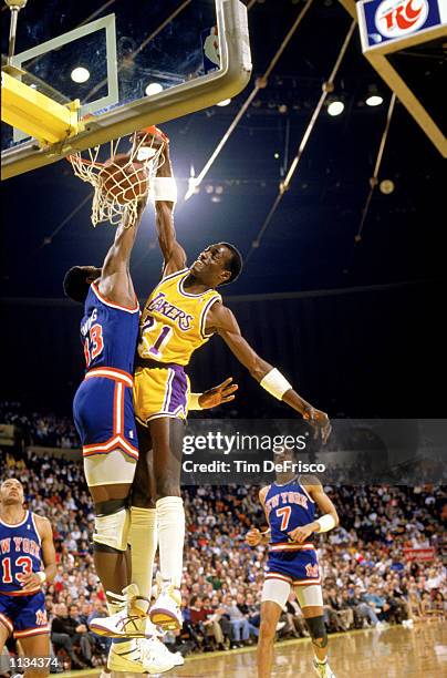 Michael Cooper of the Los Angeles Lakers dunks over Patrick Ewing of the New York Knicks during an NBA game at the Great Western Forum in Los...