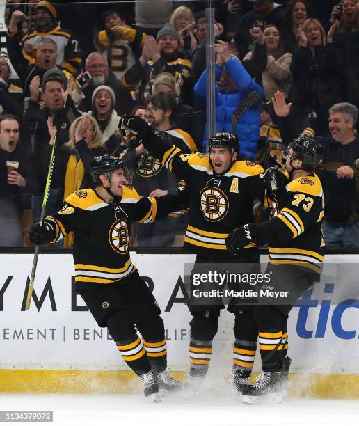 Patrice Bergeron of the Boston Bruins celebrates with John Moore and Charlie McAvoy after scoring a goal against the Florida Panthers during the...