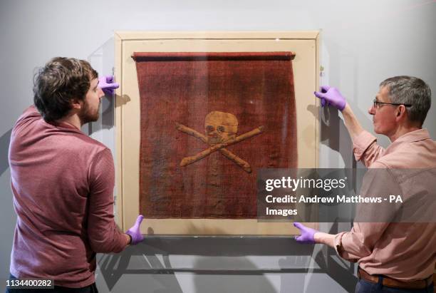 Exhibition staff at the National Museum of the Royal Navy, help hang a pirate flag which once belonged to Admiral Richard Curry, and was captured...