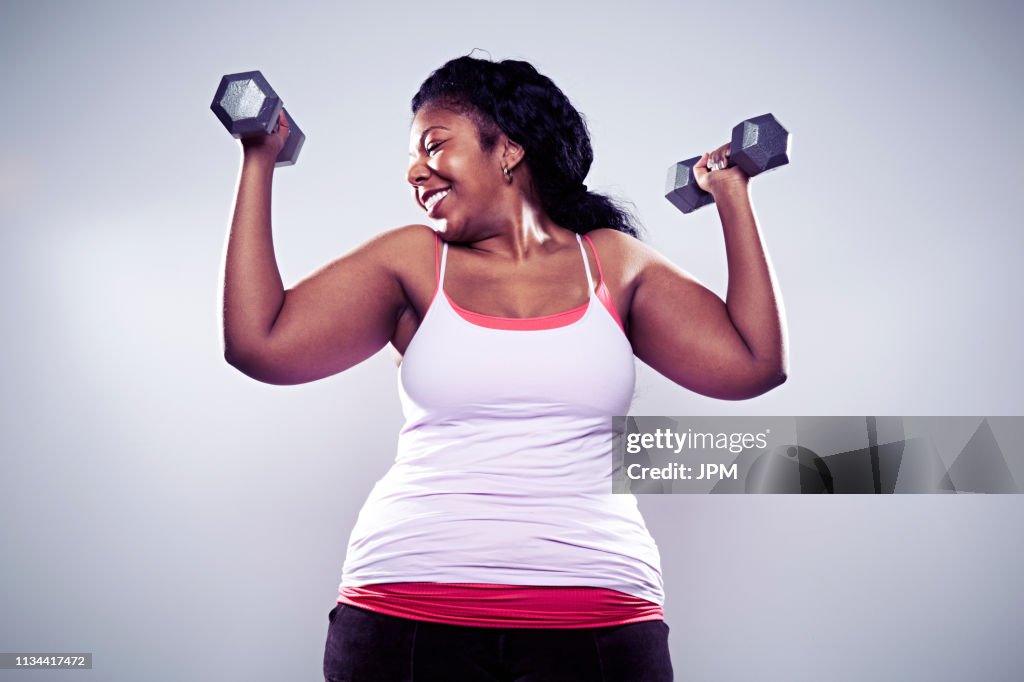 Mature woman using hand weights, smiling