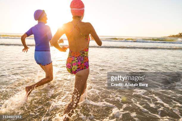 Senior women running into sea for a morning swim