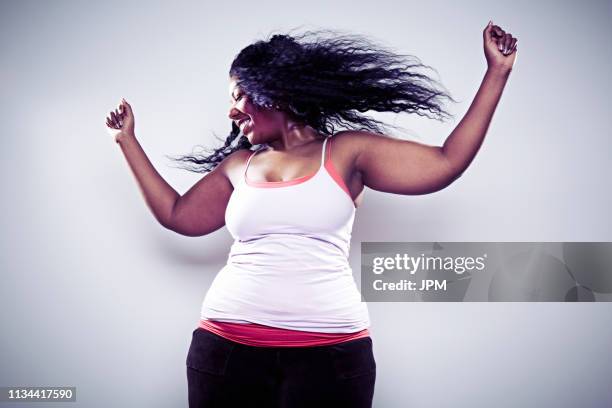 mid adult woman wearing white vest, dancing - fat woman dancing stockfoto's en -beelden