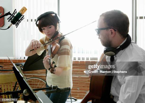 young man and woman playing violin and guitar in music room rehearsal - chorproben stock-fotos und bilder