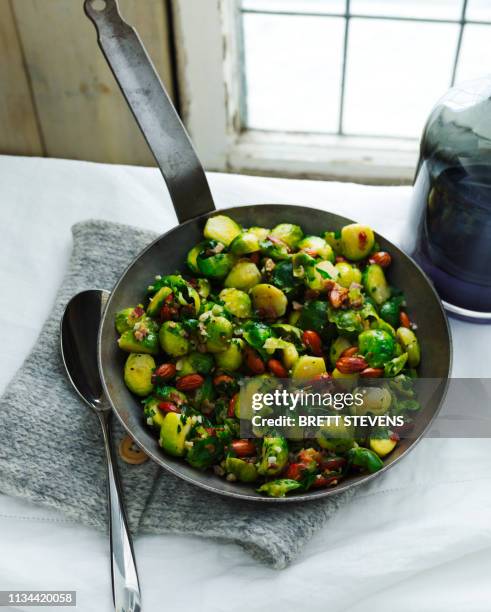 frying pan with organic brussel sprouts, herbs and nuts - brussel sprout stock pictures, royalty-free photos & images