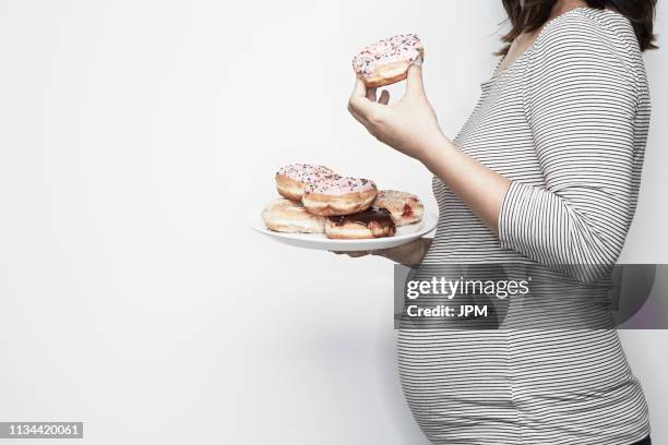 pregnant woman holding plate of doughnuts - asian pregnant woman white background photos et images de collection