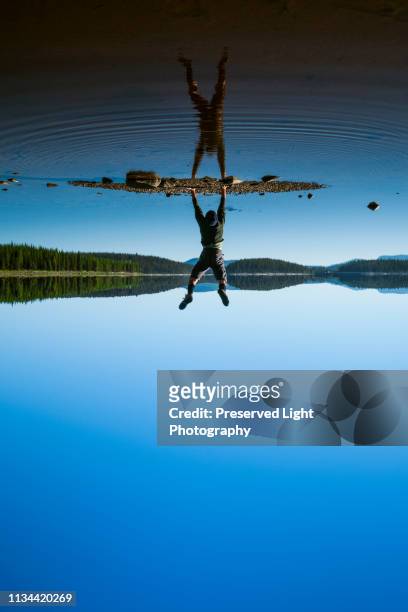 man doing handstand at mcculloch lake along the kvr trail,  okanagan highlands, british columbia, canada - ilusão - fotografias e filmes do acervo