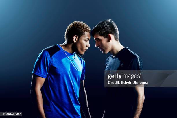 portrait of two male soccer players head to head - rivaliteit stockfoto's en -beelden
