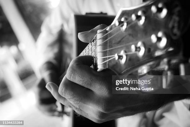 cropped hands of a man playing an acoustic guitar - country musik stock-fotos und bilder
