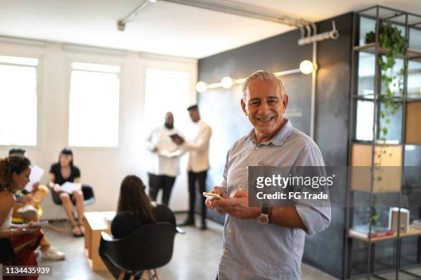 senior businessman using mobile at modern startup company - founder stock pictures, royalty-free photos & images