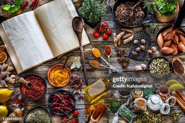 cooking concepts: cookbook with spices and herbs shot from above on rustic wooden table - cookbook stock pictures, royalty-free photos & images