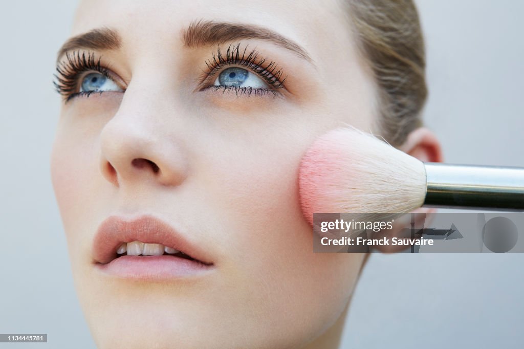 Studio shot of female model and pink blusher brush