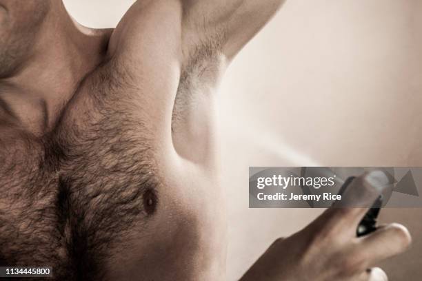 studio shot of mid adult man spraying deodorant - deodorant stock pictures, royalty-free photos & images