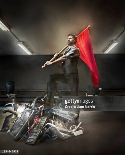 businessman holding red flag on pile of computer equipment - ribellione foto e immagini stock