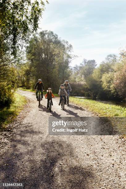 front view of family on rural road riding bicycles - erforschung stock-fotos und bilder