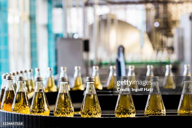 bottles on conveyor belt in bottling plant - bottling plant stock pictures, royalty-free photos & images