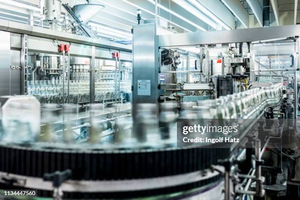 bottles of mineral water moving on conveyor belt in bottling plant - bottle factory stockfoto's en -beelden