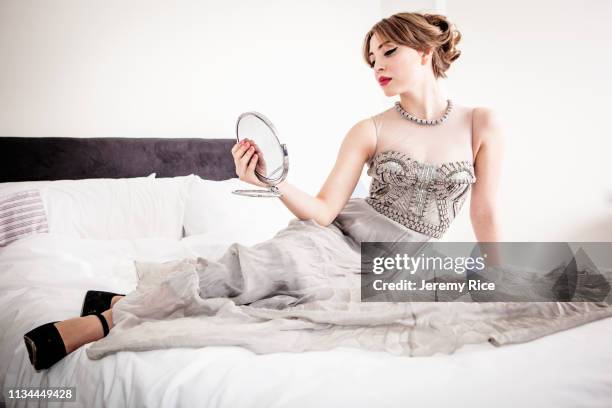 young woman in evening gown gazing at herself in mirror whilst reclining on bed - bedroom vanity stock pictures, royalty-free photos & images