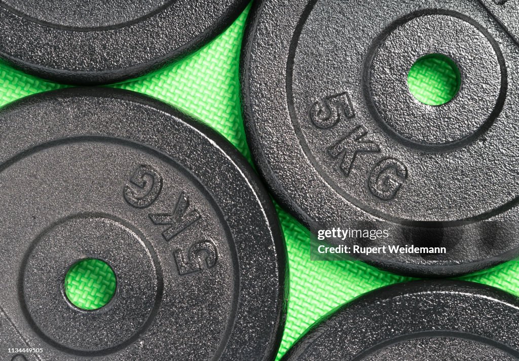 Weight plates on a colorful green weight training gym floor