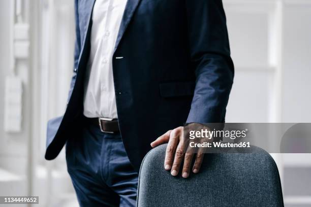 businessman standing behind office chair, partial view - geschäftskleidung stock-fotos und bilder