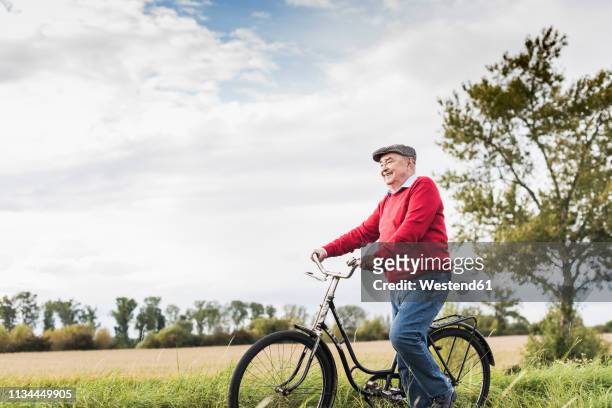 senior man pushing bicycle in rural landscape - pushing bike stock pictures, royalty-free photos & images