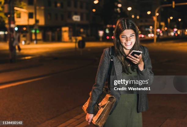 laughing young businesswoman with leather bag on the phone at night - answering machine stock pictures, royalty-free photos & images