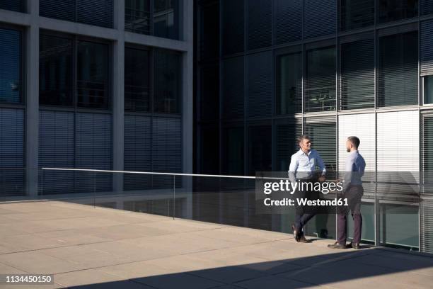 two businessmen talking outside office building - 50 sombras fotografías e imágenes de stock