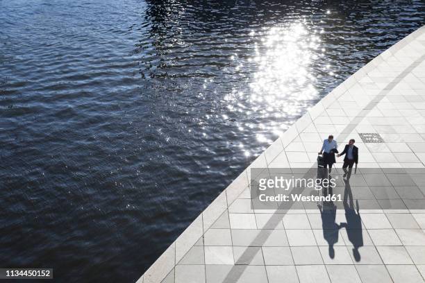two businessmen walking and talking at the riverbank - outdoor business meeting stock pictures, royalty-free photos & images