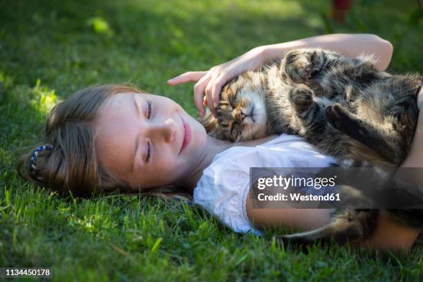 girl lying with cat in garden - summer pets stock pictures, royalty-free photos & images