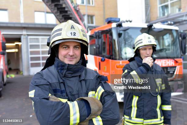 portrait of two confident firefighters in front of fire engine - fire station - fotografias e filmes do acervo