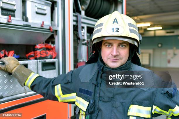 portrait of confident firefighter in front of fire engine - feuerwehr deutschland stock-fotos und bilder