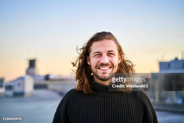 portrait of bearded young man smiling - langes haar stock-fotos und bilder