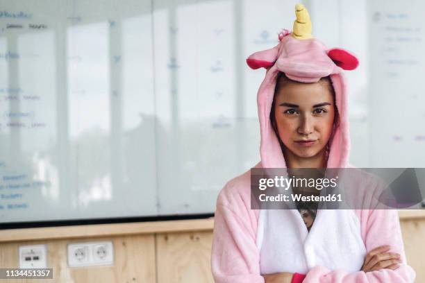 woman wearing unicorn onesie, standing in front of whiteboard, looking stubborn - teimoso - fotografias e filmes do acervo