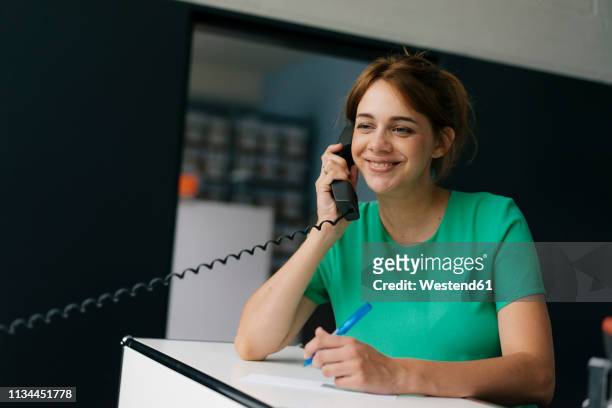 smiling woman talking on cell phone in office - festnetzanschluss stock-fotos und bilder